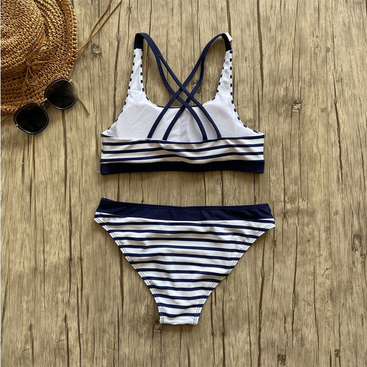 Woman smiling on a beach wearing a navy and white striped two-piece bikini with a racerback top. - Image 4