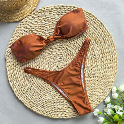 Woman wearing a black bandeau bikini top with a front knot and matching high-cut bottoms, accessorized with gold jewelry. - Image 4