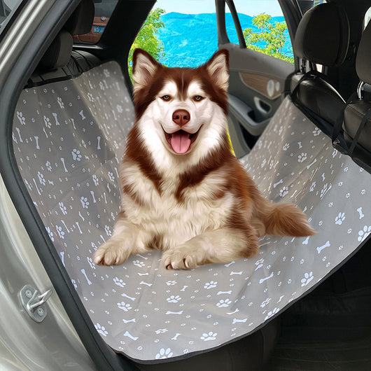 Pink car pet mat with white paw print and bone patterns, featuring black straps for securing to a rear seat.