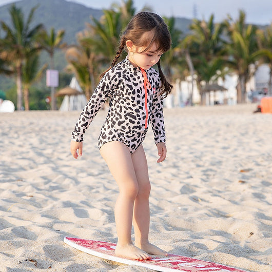 Child's long-sleeve leopard print swimsuit with a coral zipper and a matching swim cap on a white background. - Image 4