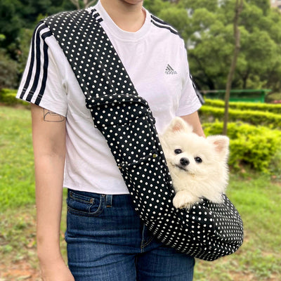 Person in white hoodie carrying a happy white dog in a navy blue pet sling bag outdoors. - Image 30