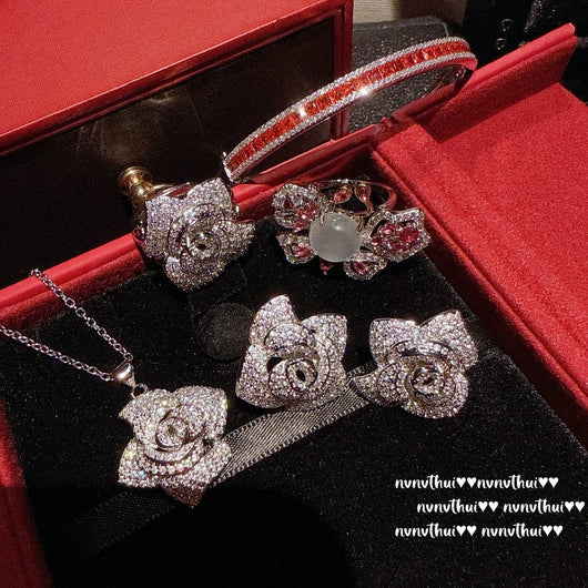 Pair of sparkling rose-shaped stud earrings, encrusted with clear gemstones, displayed in a brown jewelry box. - Image 11
