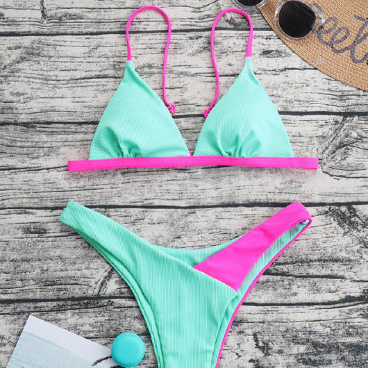 Mint green ribbed triangle bikini with hot pink trim and high-cut bottom, displayed on a wooden surface.