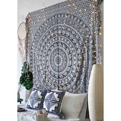 Black and white mandala tapestry with string lights hanging above a bed with blue and white patterned pillows. - Image 9