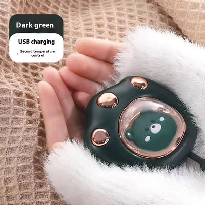 Dark green paw-shaped hand warmer and power bank with a cute bear design, held in a hand with white faux fur gloves. - Image 10