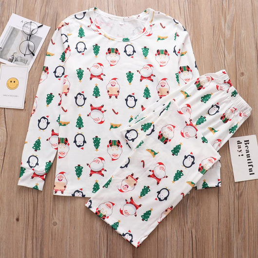Family of four wearing matching white Christmas pajamas with Santa, penguin, reindeer, and tree print. - Image 9