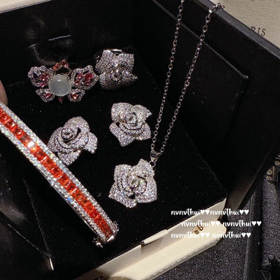 Pair of sparkling rose-shaped stud earrings, encrusted with clear gemstones, displayed in a brown jewelry box. - Image 13