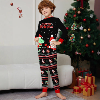 Man wearing black Christmas pajamas with a cartoon dinosaur, Santa Claus, and "Merry Christmas" text, standing by a decorated tree. - Image 4