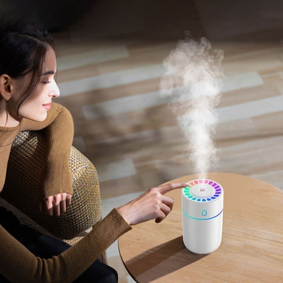 Pink cylindrical humidifier with a colorful LED light ring on top and a blue-green light band around its middle. - Image 13