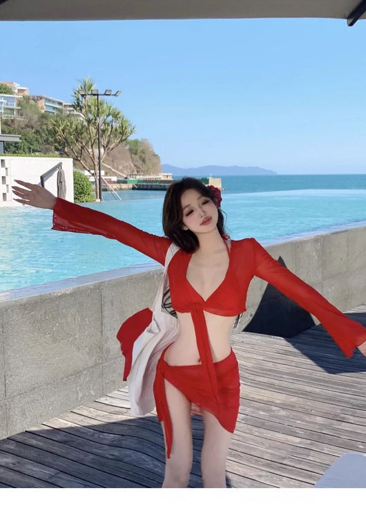 Red four-piece bikini set with sheer long-sleeve tie-front top and matching tie-front skirt on a beach. - Image 13