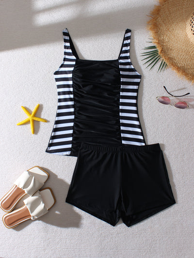 Women's black and leopard print tankini swimsuit with ruched top and swim shorts, modeled on a beach. - Image 10