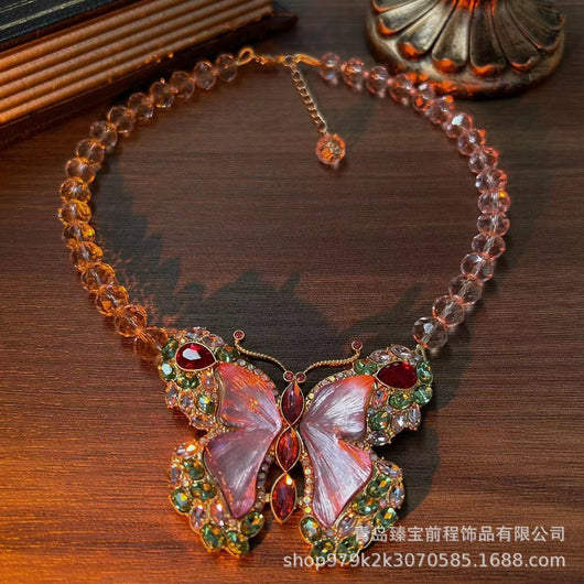 Pink enamel butterfly brooch with green, red, and clear rhinestones set in gold-toned metal. - Image 9