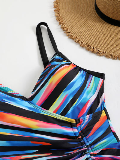 Woman in a navy and white striped tankini swimsuit with a wrap-front and side drawstring, holding a woven bag. - Image 26