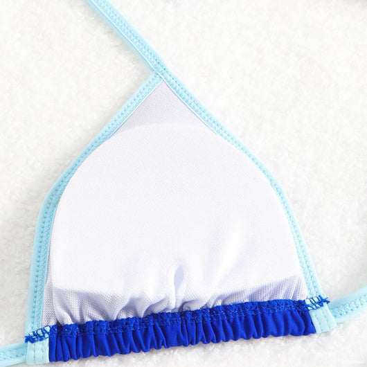 Royal blue two-piece bikini with light blue trim and tie straps, laid flat on a white textured surface. - Image 26