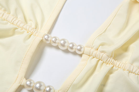 White halter monokini with deep V-neck, side cut-outs, and pearl bead embellishments on a woman at the beach. - Image 32