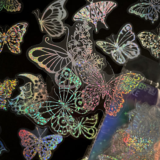 Transparent holographic butterfly laser stickers in various designs, including floral and moon elements, shown individually and in a 100-sheet pack. - Image 15
