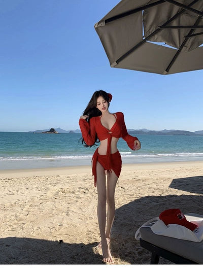 Red four-piece bikini set with sheer long-sleeve tie-front top and matching tie-front skirt on a beach. - Image 8