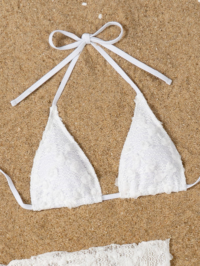 White lace halter bikini set with a matching mesh sarong, laid out on sand with sunglasses and a palm leaf. - Image 25