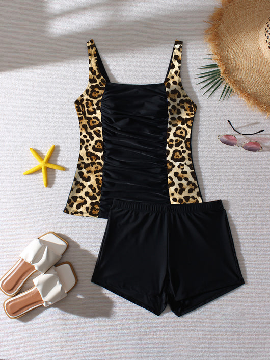 Women's black and leopard print tankini swimsuit with ruched top and swim shorts, modeled on a beach. - Image 18