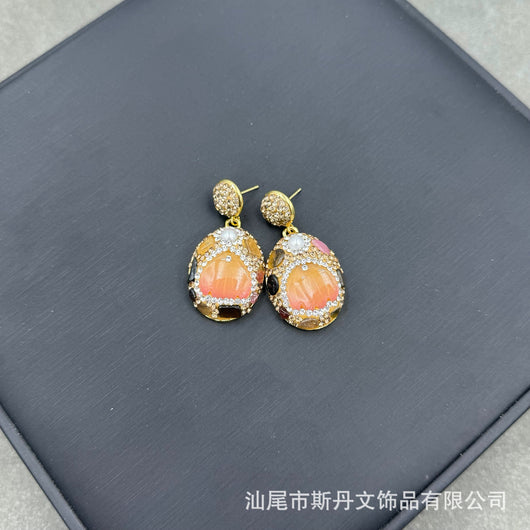 Gold-toned dangle earrings with oval drops, featuring a carved pink flower, clear rhinestones, and multi-colored tourmaline. - Image 8
