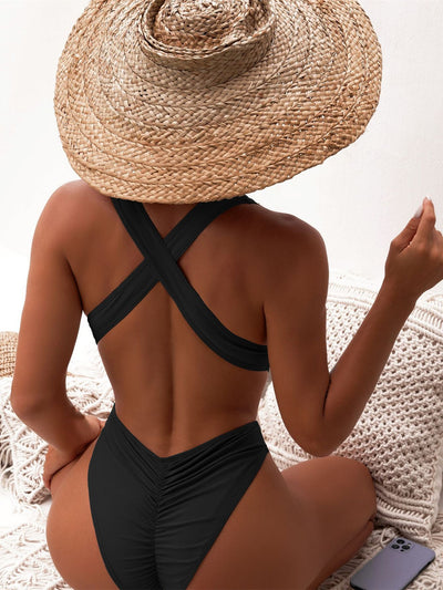 Woman in a black one-piece swimsuit with a deep V-neck and criss-cross waist cutouts, wearing a straw hat. - Image 17