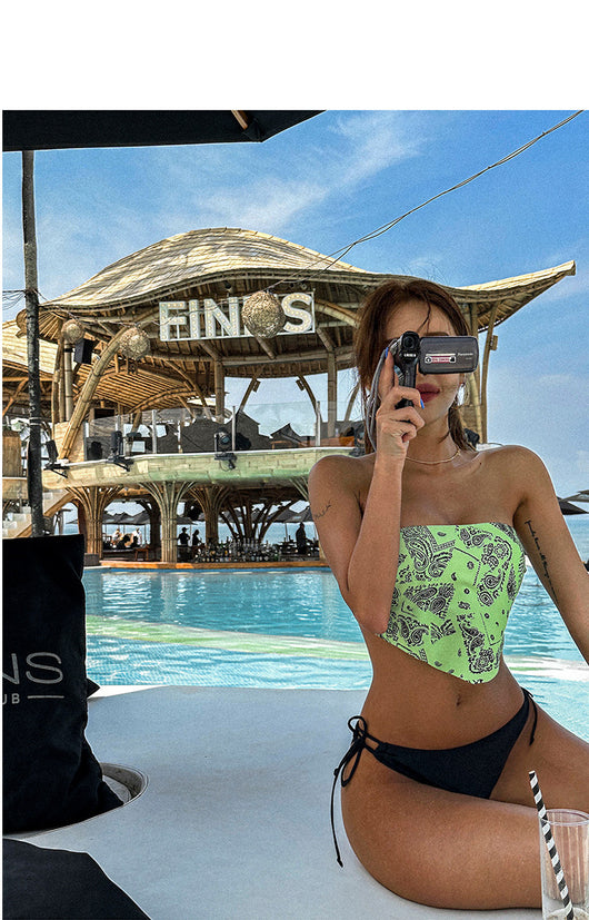 Lime green bandana print bandeau bikini top with black low-rise tie-side bottoms on a woman by a pool. - Image 12