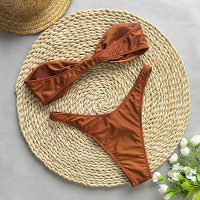 Woman wearing a black bandeau bikini top with a front knot and matching high-cut bottoms, accessorized with gold jewelry. - Image 13