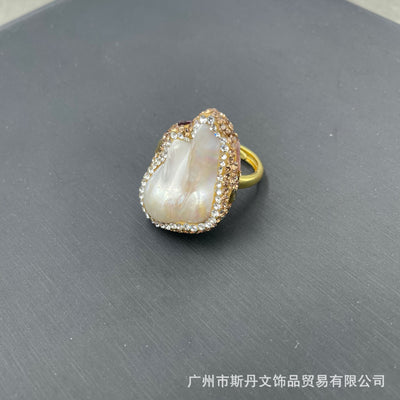 Gold-toned ring with a large, irregularly shaped white freshwater pearl centerpiece, framed by clear and champagne rhinestones. - Image 8