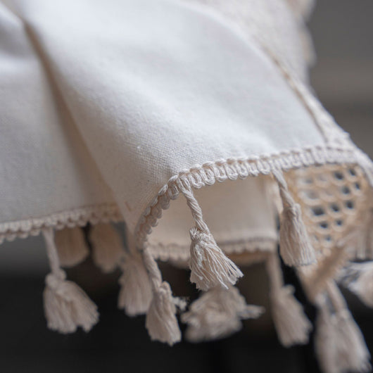 Close-up of a beige semi-transparent curtain with a delicate crochet lace trim and decorative tassels. - Image 17