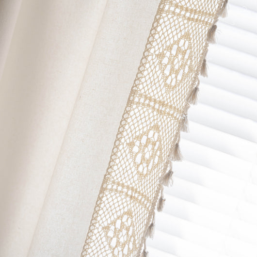 Close-up of a beige semi-transparent curtain with a delicate crochet lace trim and decorative tassels. - Image 28
