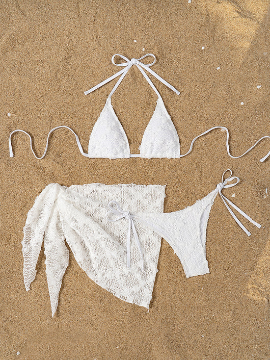 White lace halter bikini set with a matching mesh sarong, laid out on sand with sunglasses and a palm leaf. - Image 9
