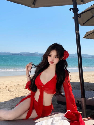 Red four-piece bikini set with sheer long-sleeve tie-front top and matching tie-front skirt on a beach. - Image 16