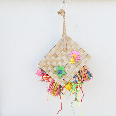 Colorful parrot foraging toy with woven palm leaf, a bell, wooden star, and shredded paper, hanging against a white wall. - Image 13
