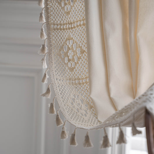 Close-up of a beige semi-transparent curtain with a delicate crochet lace trim and decorative tassels. - Image 22