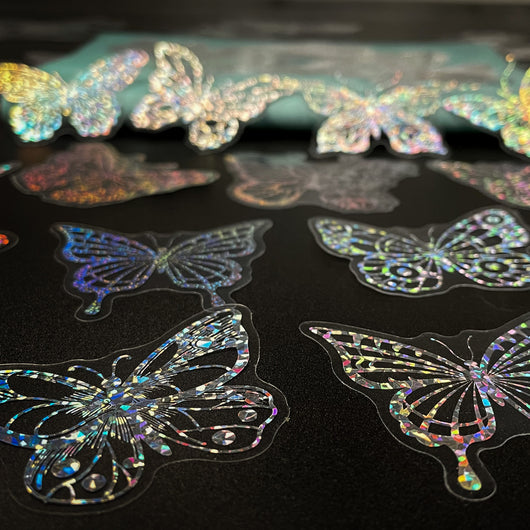 Transparent holographic butterfly laser stickers in various designs, including floral and moon elements, shown individually and in a 100-sheet pack. - Image 18
