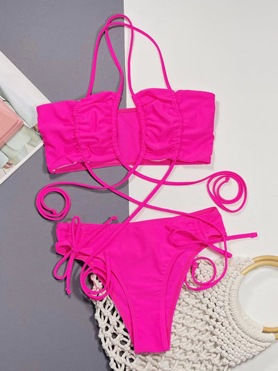 Neon pink lace-up bikini with a bandeau top and high-cut bottom, laid flat on a split gray and white background. - Image 15