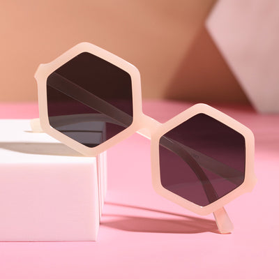 Red hexagonal children's sunglasses with dark lenses on a pink surface with a white block. - Image 10