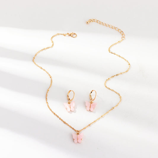 Blue resin butterfly necklace and earring set with gold-tone chains and findings, displayed on a light background.