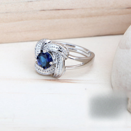 Blue zirconia jewelry set with silver-toned necklace, bracelet, ring, and earrings, featuring swirling designs.