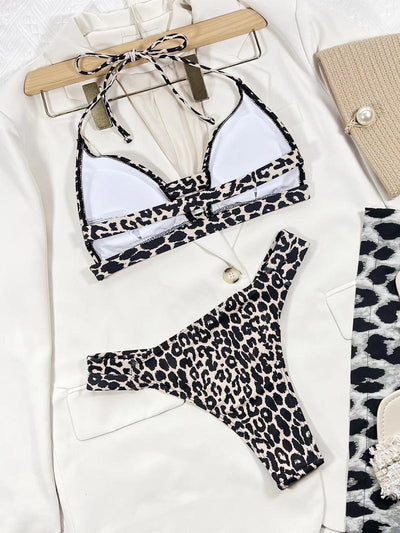Leopard print high-waisted bikini with a halter neck top and front cutout, worn by a woman lounging outdoors. - Image 8