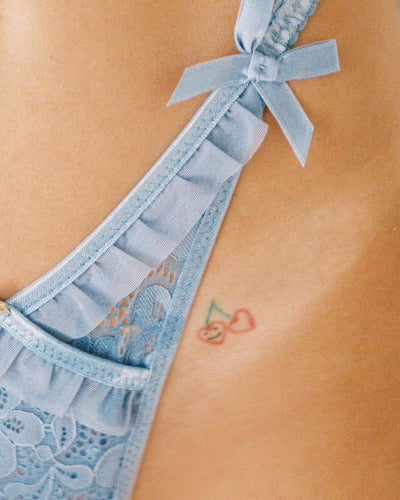 Light blue lace bralette and thong lingerie set with bow details and ruffle trim, displayed on a light surface. - Image 14