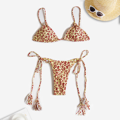 Black string bikini with wrap-around straps and gold-tone rings with tassels modeled on a beach. - Image 16