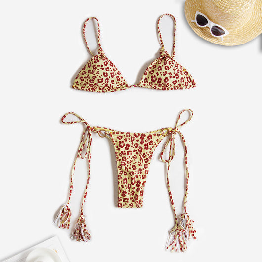 Black string bikini with wrap-around straps and gold-tone rings with tassels modeled on a beach. - Image 16