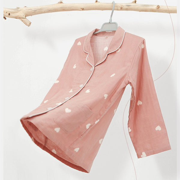 Pink long-sleeved pajama set for children with an all-over cherry print, Peter Pan collar, and matching pants.