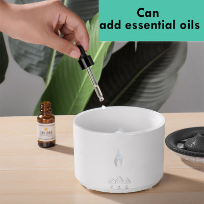 White ultrasonic essential oil diffuser with orange flame effect mist, alongside a gift set of Lavender, Peppermint, Tea Tree, and Sweet Orange essential oils. - Image 3