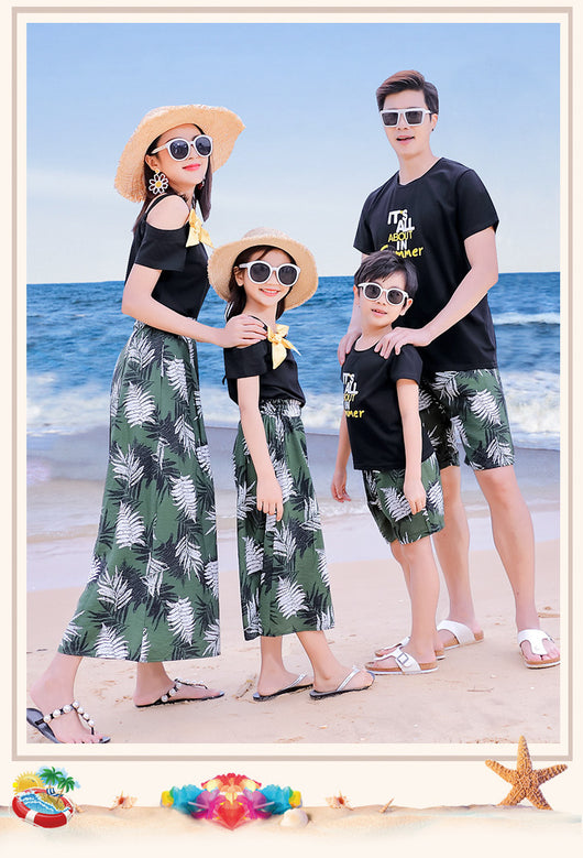Family of four in matching black and green tropical print outfits on a beach, featuring t-shirts, shorts, skirt, and wide-leg pants. - Image 7