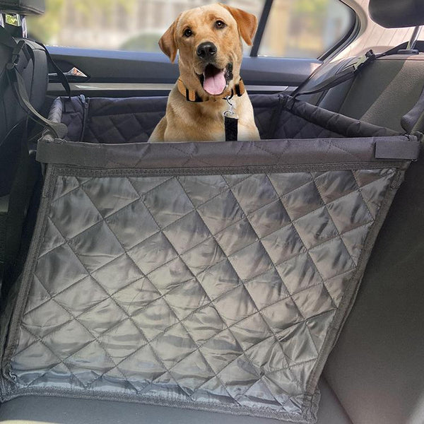 Golden retriever in a dark grey quilted pet car seat, secured in the back seat of a car.