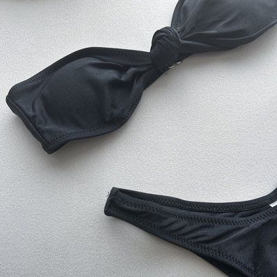 Woman wearing a black bandeau bikini top with a front knot and matching high-cut bottoms, accessorized with gold jewelry. - Image 20