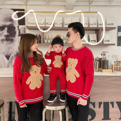 Family of three wearing matching red cable-knit sweaters with a brown teddy bear appliqué and striped trim. - Image 5