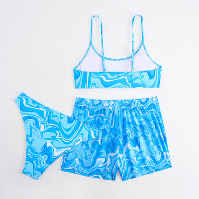 Red, orange, and white abstract swirl print three-piece bikini set with matching shorts, shown with a straw hat and sunglasses. - Image 14